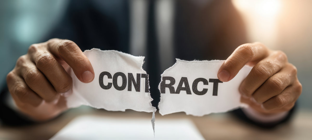 The contract being torn by businessman signaling deal termination and legal breach