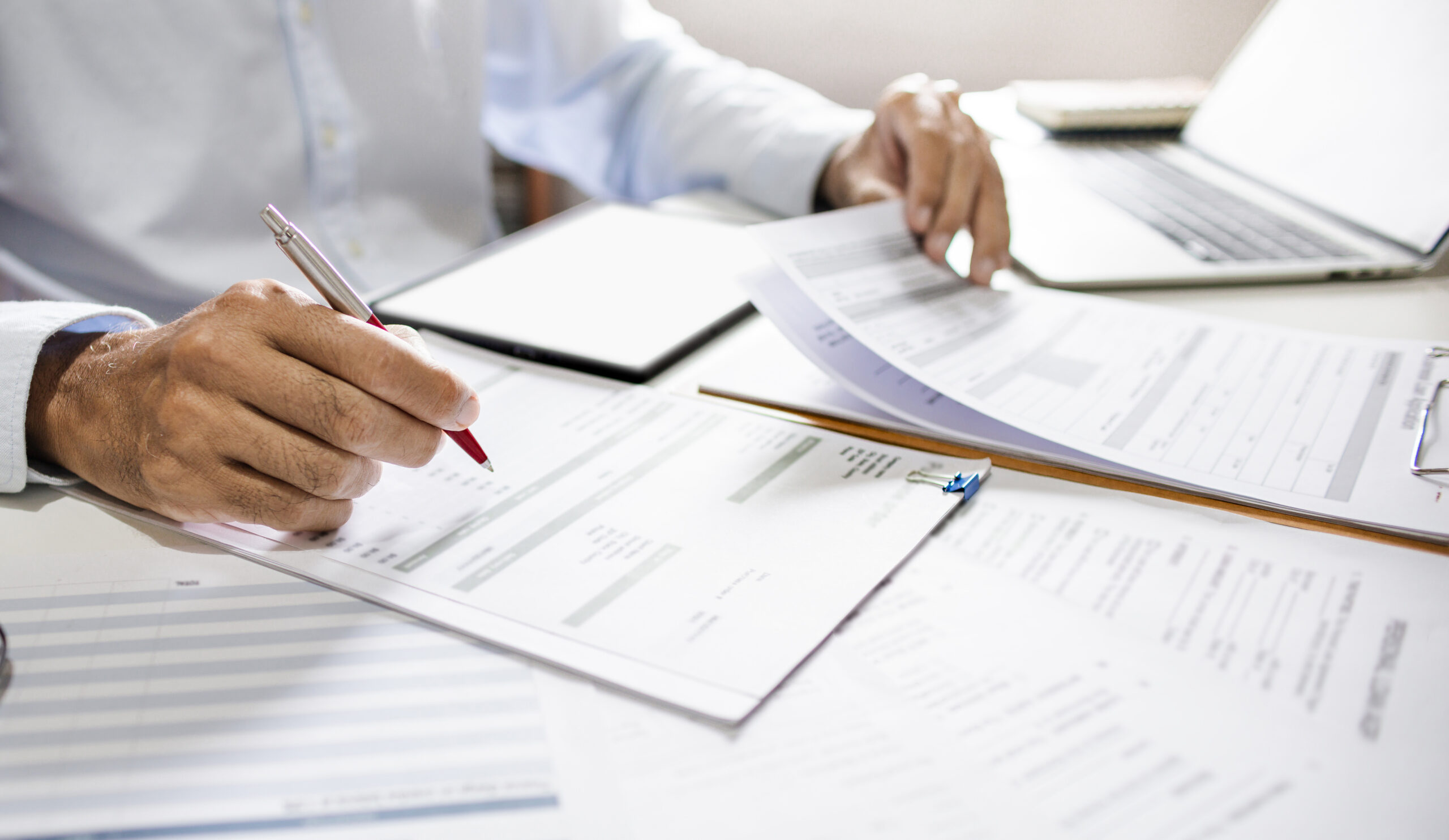 Asian businessman reviewing document report at office working with laptop, professional lawyer reading and checking financial documents or insurance contract before sign, Close-up shot