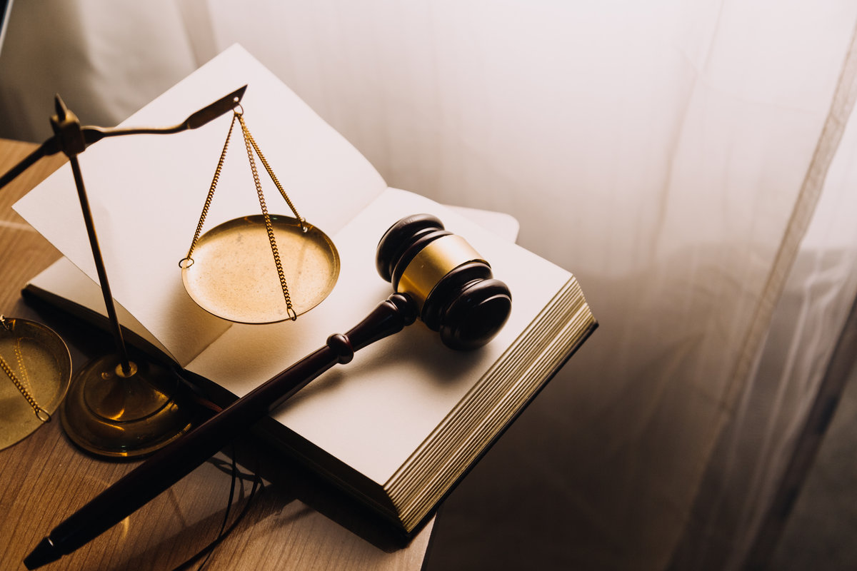Justice and law concept.Male judge in a courtroom with the gavel, working with, computer and docking keyboard, eyeglasses, on table in morning light